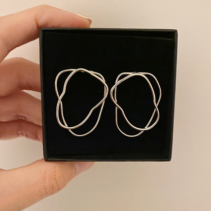 Dubbele Fine Lines oorbellen in een doosje, in de hand gehouden